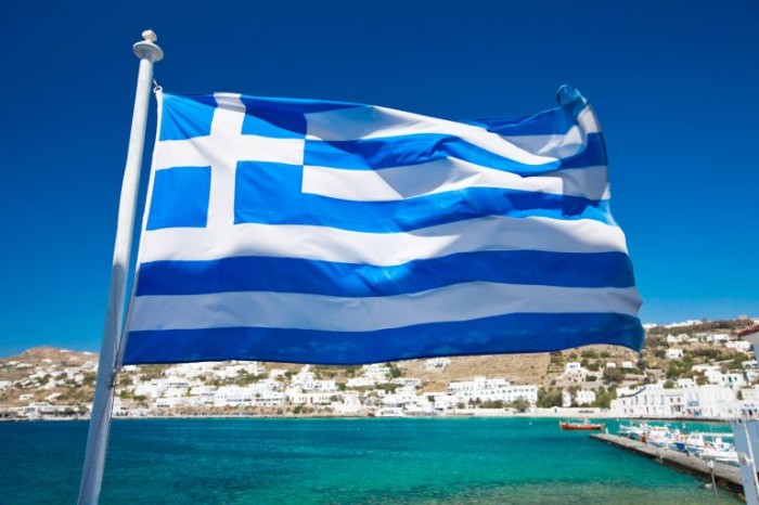 Bandeira da Grécia com Mikonos ao fundo - (Foto: Depositphotos)